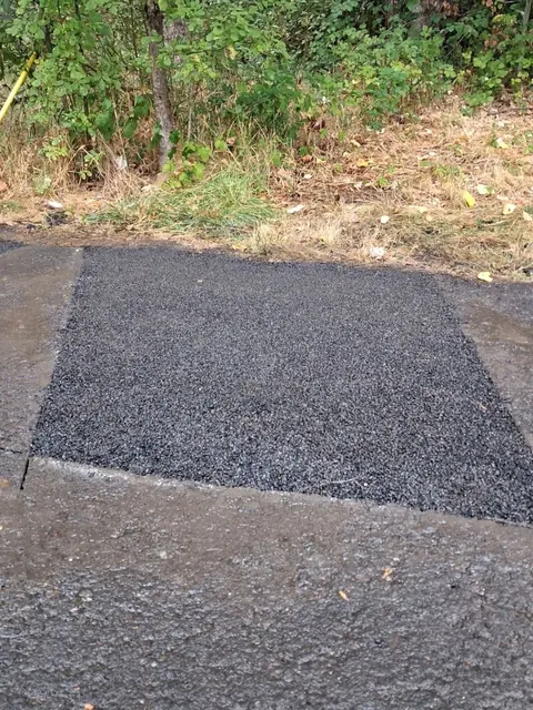 A rectangular dark asphalt patch contrasts with the older pavement around it.