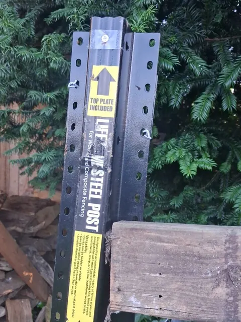 A steel replacement post beside the old weathered rail, where the rotted wood post came out.