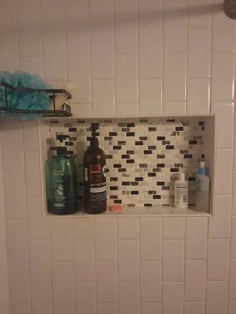 Before the remodel: a mosaic-backed niche set into the original white tile wall.