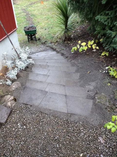 Rectangular pavers form a small landing and path beside a planted border.